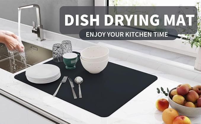 Black dish drying mat beside the sink with washed plates, bowls, glasses and cutlery