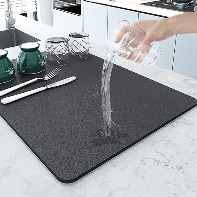 Water poured onto a black dish drying mat next to cups and cutlery