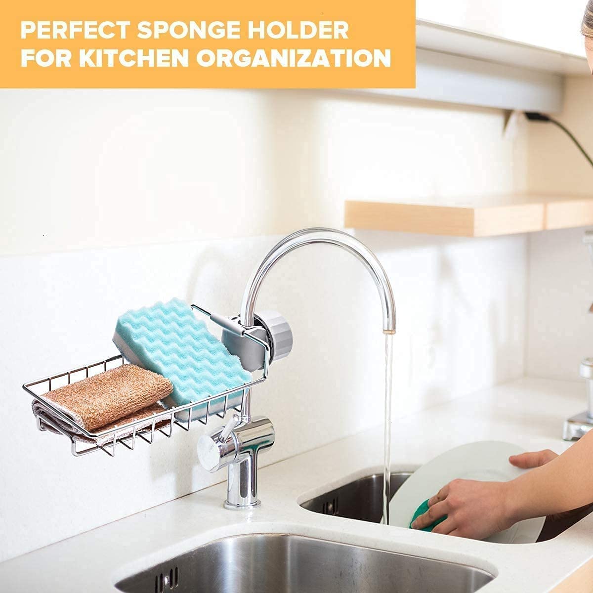 Steel tap rack holding a sponge and a cloth on a kitchen tap while dishes are washed in the sink