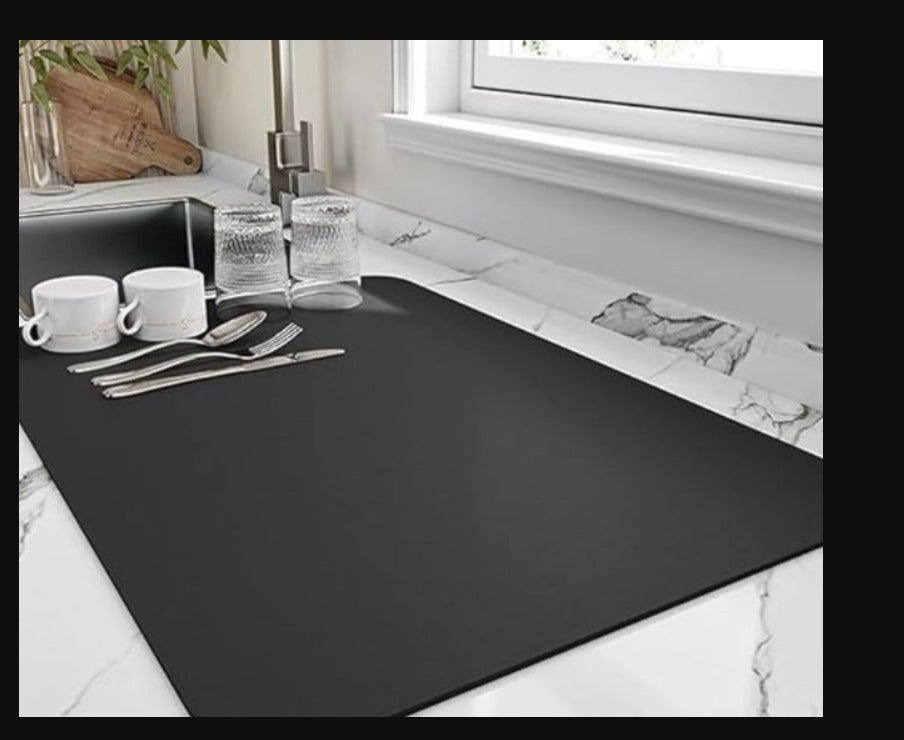 Black dish drying mat under a kitchen window with cups and glasses